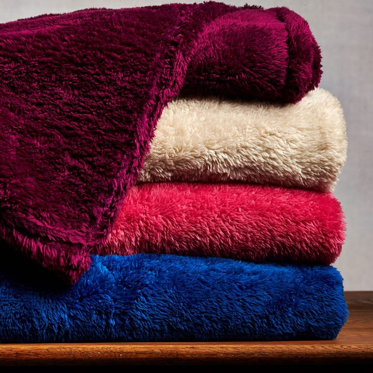 A stack of soft, colorful mink blankets crafted by the top mink blanket manufacturer in India, Birmi Group.